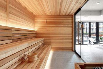A wooden sauna room with a glass door leading to a balcony.