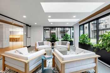 A modern living room with white furniture and a large window.