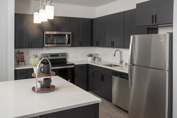 A modern kitchen with a stainless steel refrigerator and black cabinets