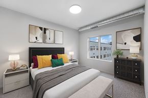 St. Paul apartment for rent - A bedroom with a bed, nightstand, and a window with a view of a building at Soul Apartments, Minnesota 55107