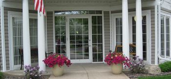 A porch with two pillars and two potted flowers
