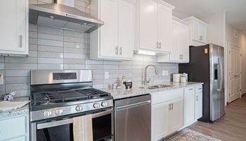 A kitchen with white cabinets and stainless steel appliances
