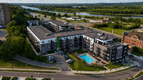 South St. Paul apartment for rent - A large apartment complex with a swimming pool and a river in the background.