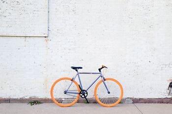 An orange and blue bike parked next to a white brick wall