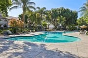 Santa Clara apartment for rent - A large outdoor swimming pool surrounded by trees and a patio area with chairs.