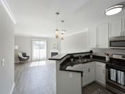 Canoga Park apartment for rent - an empty kitchen and living room with white cabinets and black counter tops at Warner Center Townhomes, California, 91303