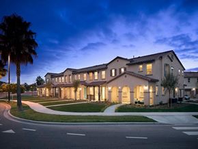 Oxnard apartment for rent - a large building with a palm tree in front of it at The Vines at Riverpark, LLC, Oxnard, CA