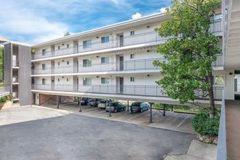 A large white apartment building with cars parked in front of it