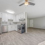 El Cajon apartment for rent - an empty kitchen with white cabinets and a ceiling fan at The Arches Apartments, El Cajon California