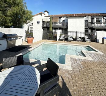 A resort style pool with a table and chairs around it