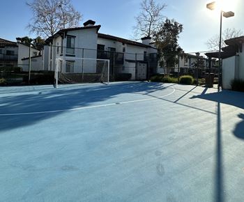 A tennis court in front of some apartments on a sunny day
