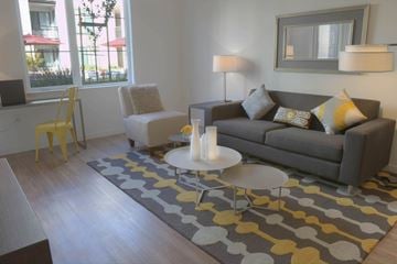 Mountain View apartment for rent - A grey couch with yellow and white pillows sits in a living room with a grey rug and a white coffee table.