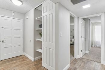A walk in closet with white closets and mirrored doors