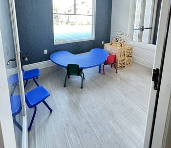A childs play room with a blue table and chairs
