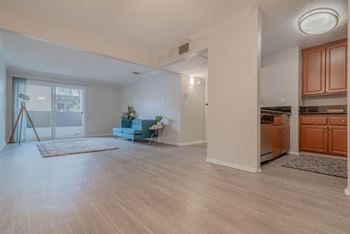 An open living room with a kitchen and a door to a balcony