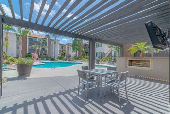 A patio with a table and chairs next to a pool