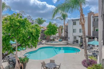 A swimming pool with tables and chairs and palm trees