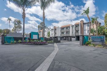 An empty parking lot in front of a building with palm trees