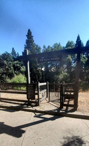 A park entrance with a bench and a gate