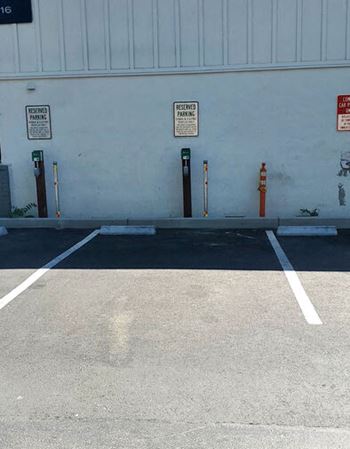 A parking lot with parking meters and a blue building