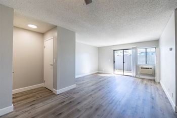 An empty living room with wood flooring and a door to a balcony
