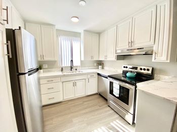 A white kitchen with stainless steel appliances and white cabinets