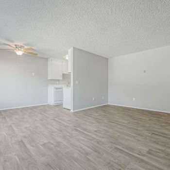 An empty living room and kitchen with a ceiling fan