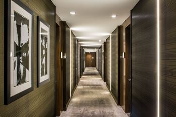 A long hallway with a series of doors on the right and framed pictures on the left.