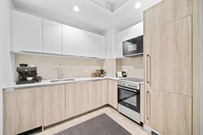 New York apartment for rent - A kitchen with wooden cabinets and a white countertop.