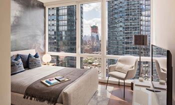 A bedroom with a bed and a view of the city