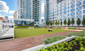 A rendering of a rooftop terrace with a lawn and buildings in the background