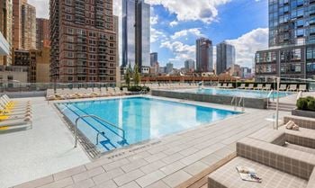 The pool on the rooftop of a building with a city in the background