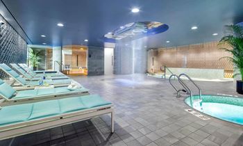 A spa with a jacuzzi and a pool in a room with chairs