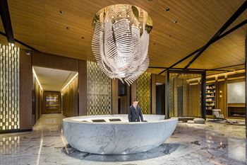 A man stands in the lobby of a hotel with a large circular desk and a