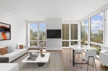 A living room with a white couch and a table and a large window
