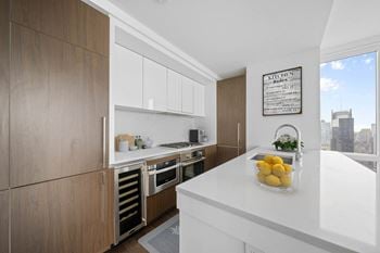 A kitchen with a white counter top and wooden cabinets