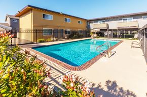 San Leandro apartment for rent - A pool surrounded by a black fence and a yellow building.