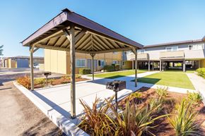 San Leandro apartment for rent - A building with a brown roof and a parking lot in front.