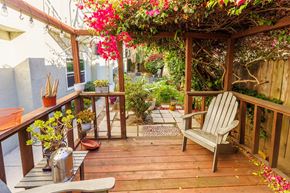 Alameda apartment for rent - A wooden deck with a bench and a table with flowers on it.