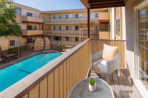 San Leandro apartment for rent - A balcony with a table and chairs overlooking a pool.