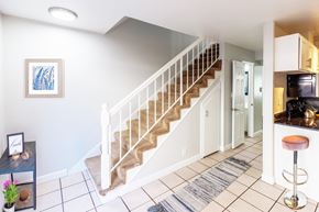 Hayward apartment for rent - A staircase with a white railing and beige carpeted steps leads to a kitchen area.