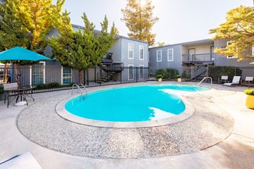 Concord apartment for rent - A round swimming pool surrounded by a concrete patio and a building in the background.