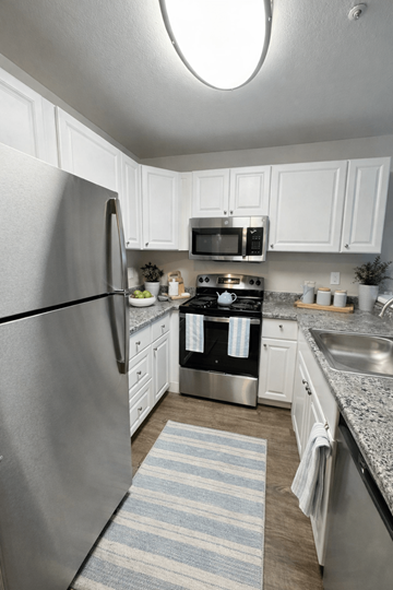 Concord apartment for rent - A kitchen with a refrigerator, microwave, oven, and sink.