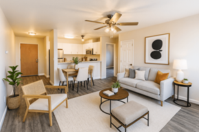 Concord apartment for rent - A living room with a white couch, a wooden chair, and a ceiling fan.