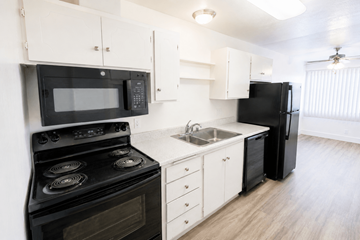 San Leandro apartment for rent - A black stove and microwave in a white kitchen.