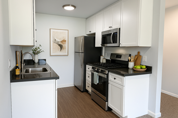Hayward apartment for rent - A kitchen with white cabinets and black countertops.