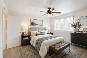 San Leandro apartment for rent - A bedroom with a bed, a bench, and a ceiling fan.