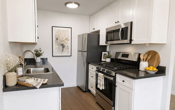 Hayward apartment for rent - A modern kitchen with white cabinets and black countertops.