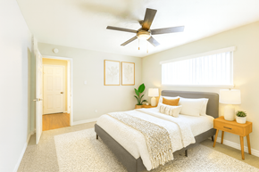 Concord apartment for rent - A bedroom with a bed, a ceiling fan, and a nightstand with a plant on it.