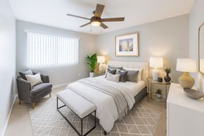 Hayward apartment for rent - A bedroom with a large bed, a chair, and a ceiling fan.